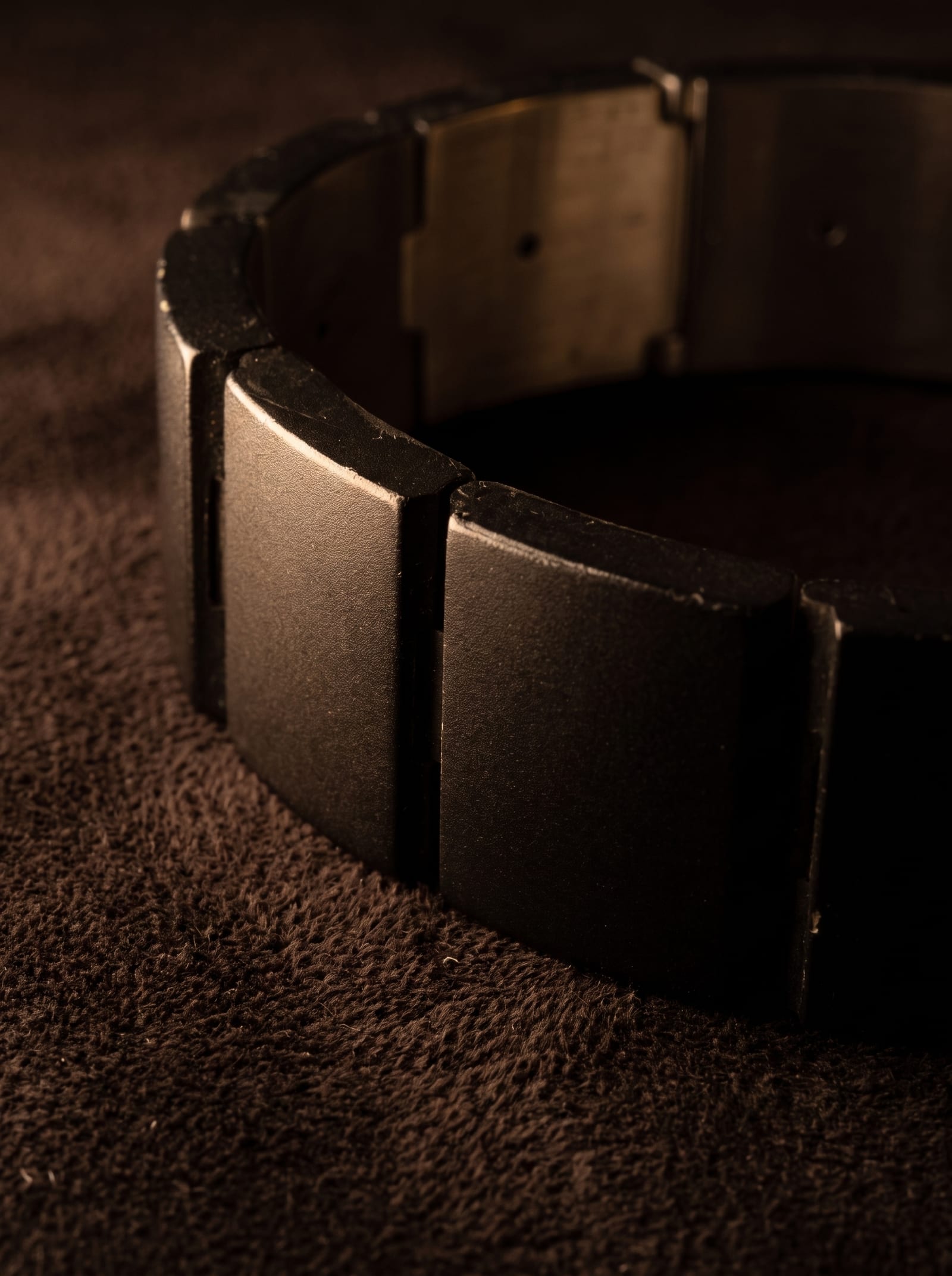The bracelet in the Onyx finish, lit low against dark cloth